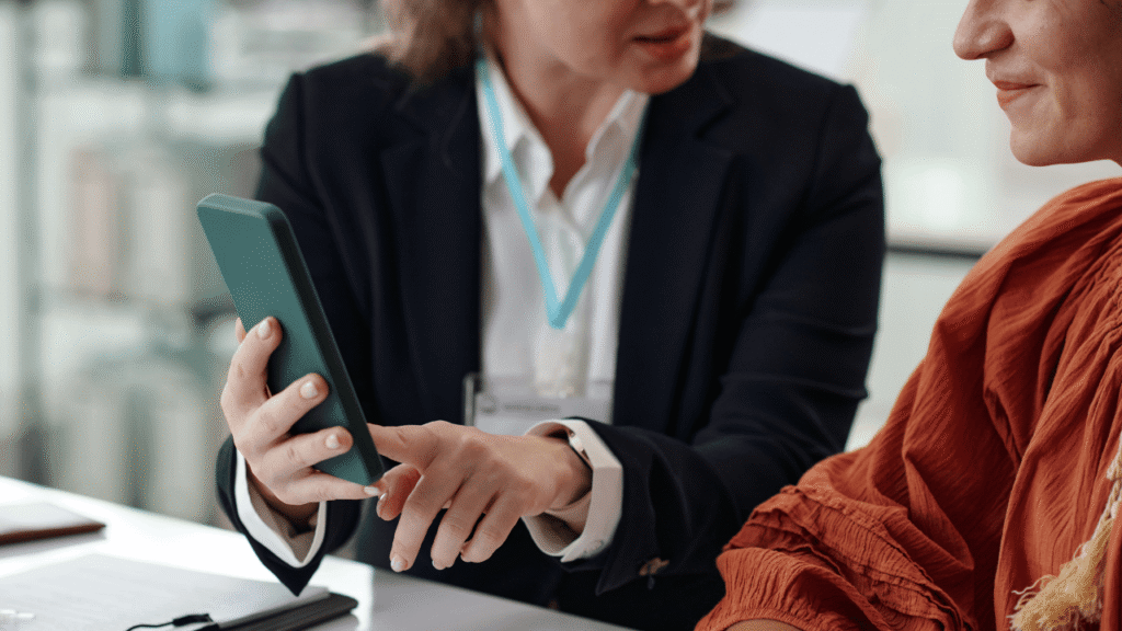 Bad debt proof finance meeting where a business advisor shows a client a payment-risk checklist and receivables tracker on a smartphone to help prevent overdue invoices and improve cash flow.