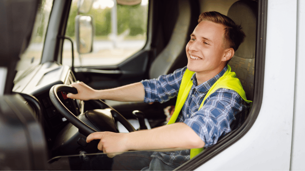 Smiling driver in a truck cab, representing essential truck driver hard skills like vehicle control and safe operation.