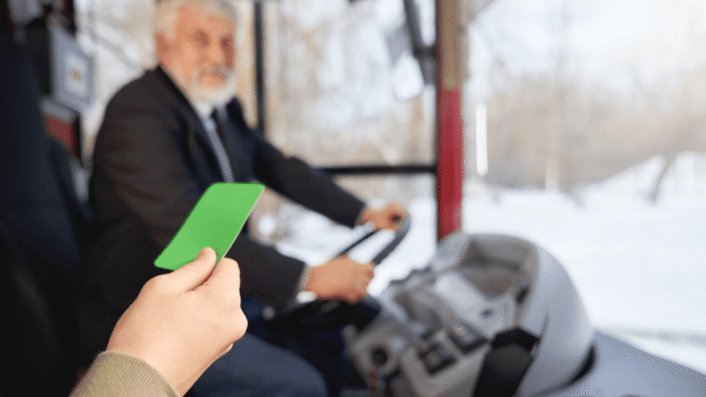 ELD affects driver pay: truck driver in the cab while a hand holds an electronic logging device card/phone in the foreground, highlighting how logged hours and duty status can impact wages.
