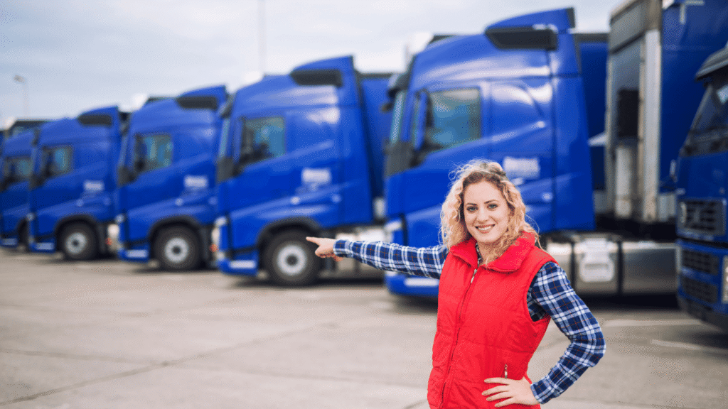 Fleet manager pointing at a lineup of blue trucks to build a brand in trucking through consistent fleet image.